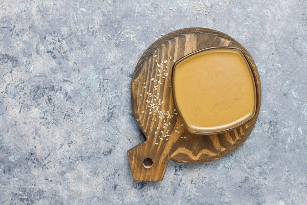 Creamy lemon herb tahini sauce displayed on wooden board