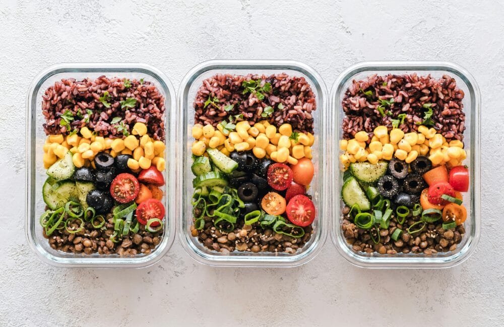 Colorful vegetarian meal prep ideas with bowls of rice and salad vegetables in glass containers