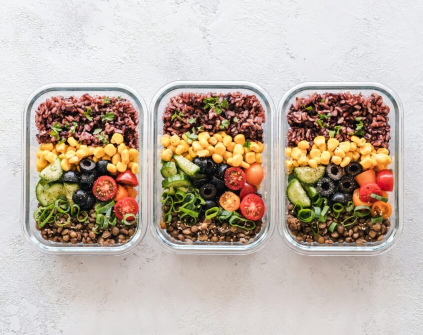 Colorful vegetarian meal prep ideas with bowls of rice and salad vegetables in glass containers